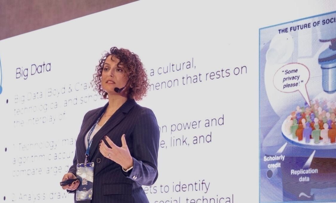 Tuba Bircan giving a talk on big data with a headset microphone in front of a large slide